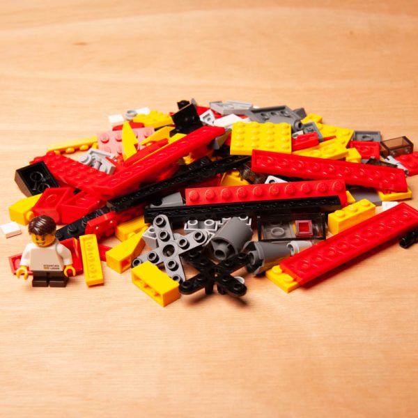 Een hand opent een gripzakje met daarin een selectie LEGO-blokjes.